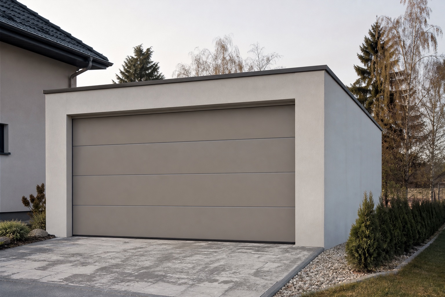 Schlichte Fertiggarage mit flachem Dach und breitem Sektionaltor auf einem Grundstück